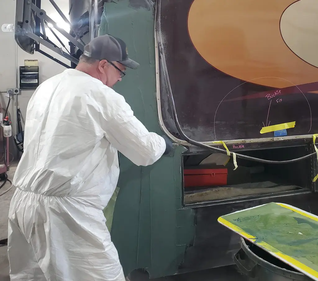 a worker fixing a bent section of framing on an RV